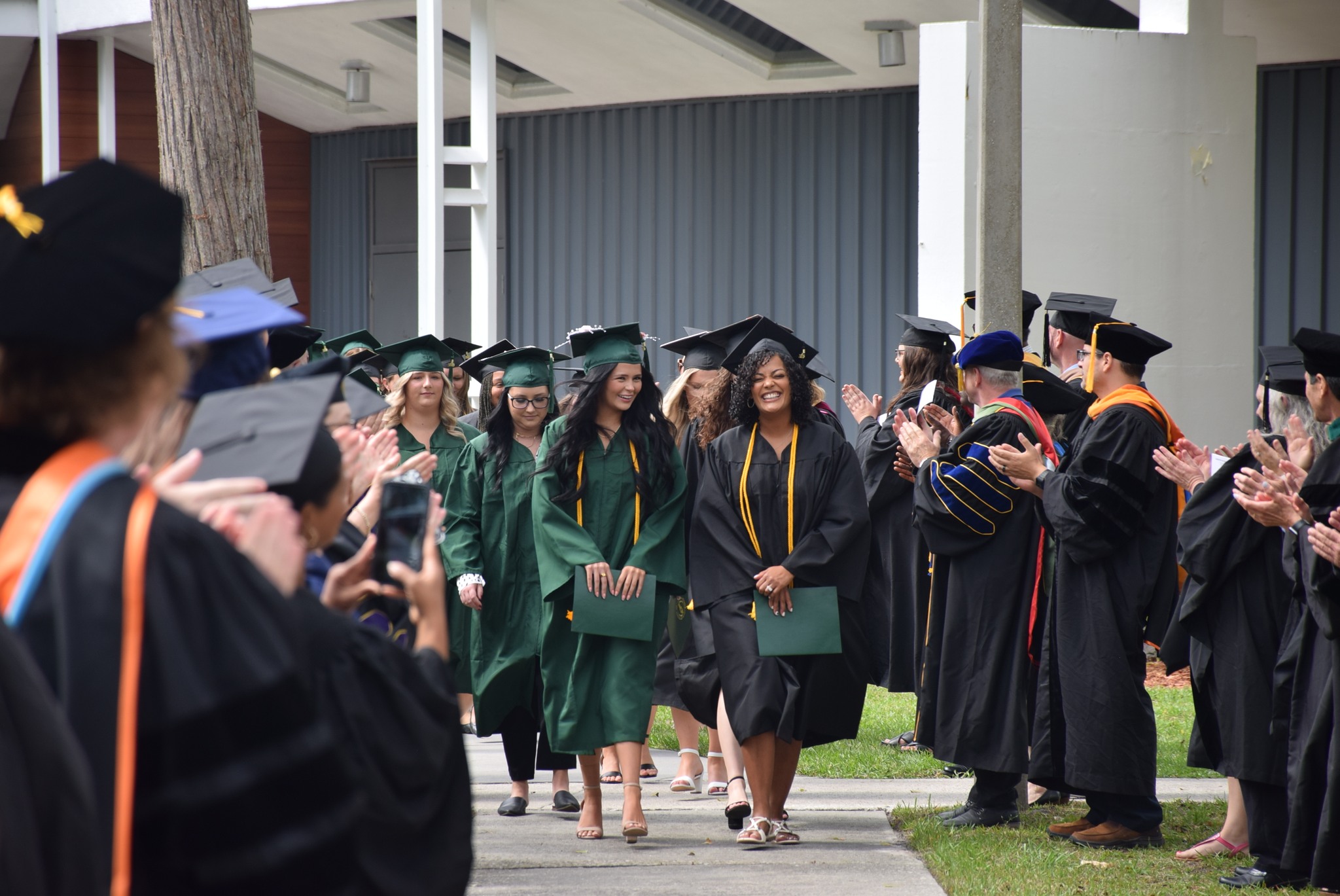 Outdoor; graduates walk in line after ceremony