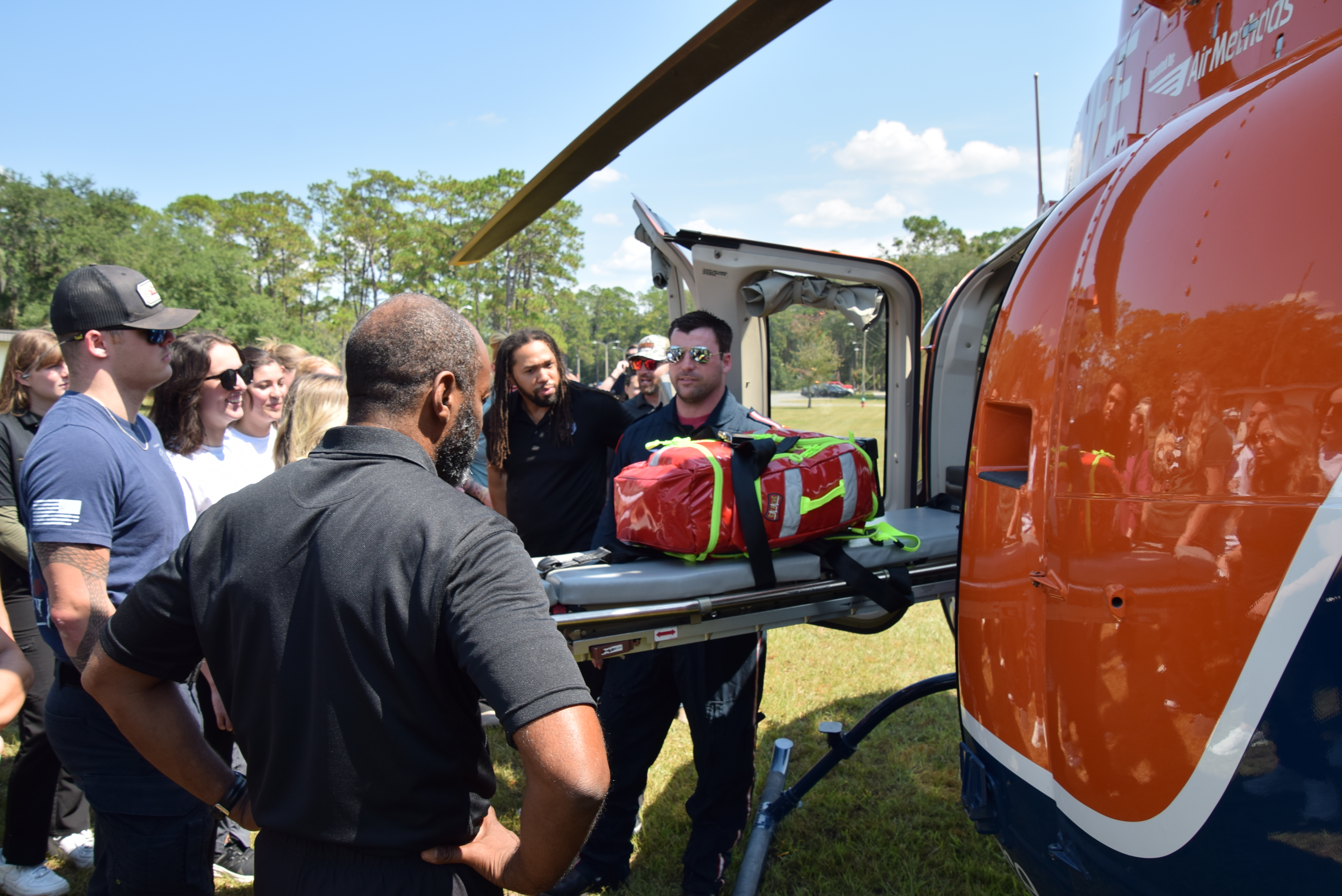 Students gather near helicopter; crew member demonstrates operations.